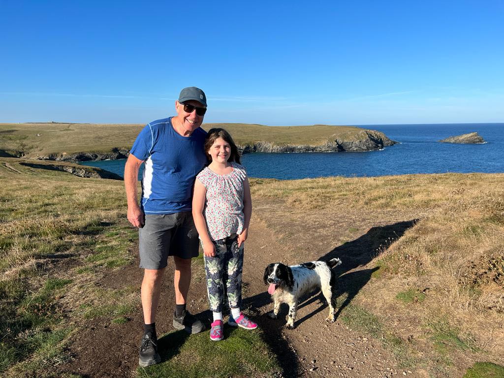 man, girl and brown and white dog walking on Cornwall coast path