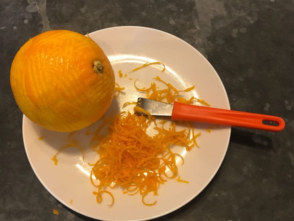 Orange juice and orange zest on white plate