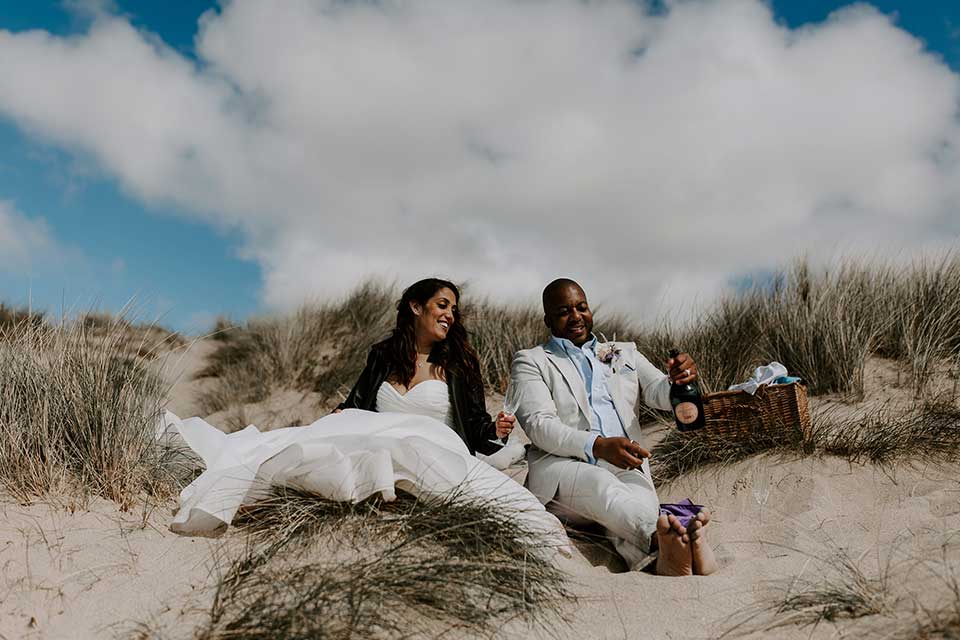 wedding day couple enjoying champagne on beach in Cornwall