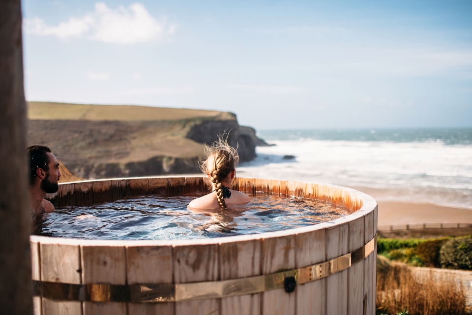 Woman in a wooden hot tub looking towards the sea