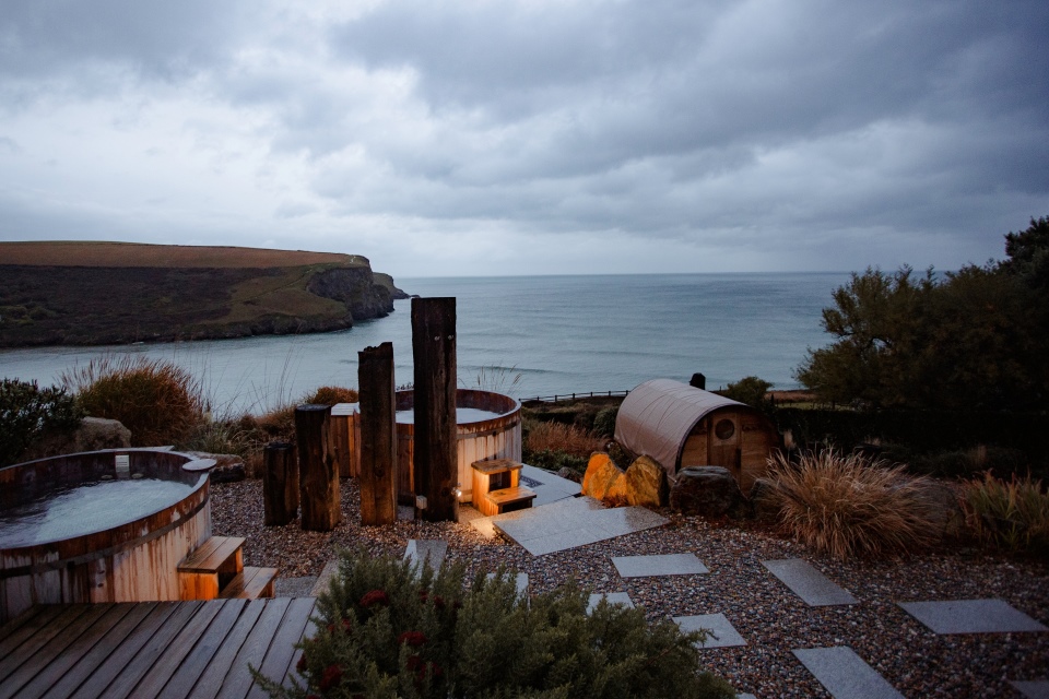 Hot tub lit up by candles, with the sea and cliffs in the background
