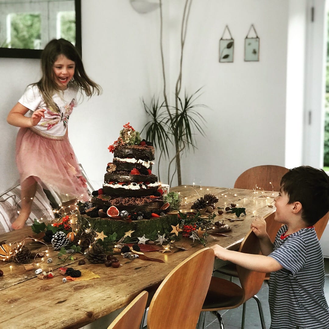 young boy and young girl playing around party table with birthday cake
