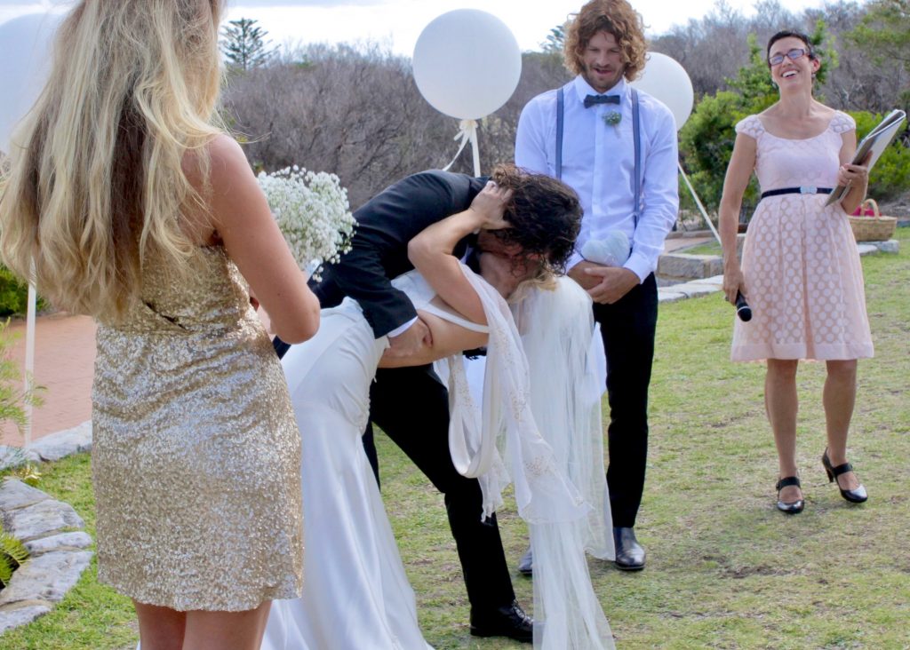 Kiss at real wedding bride and groom and smiling guests
