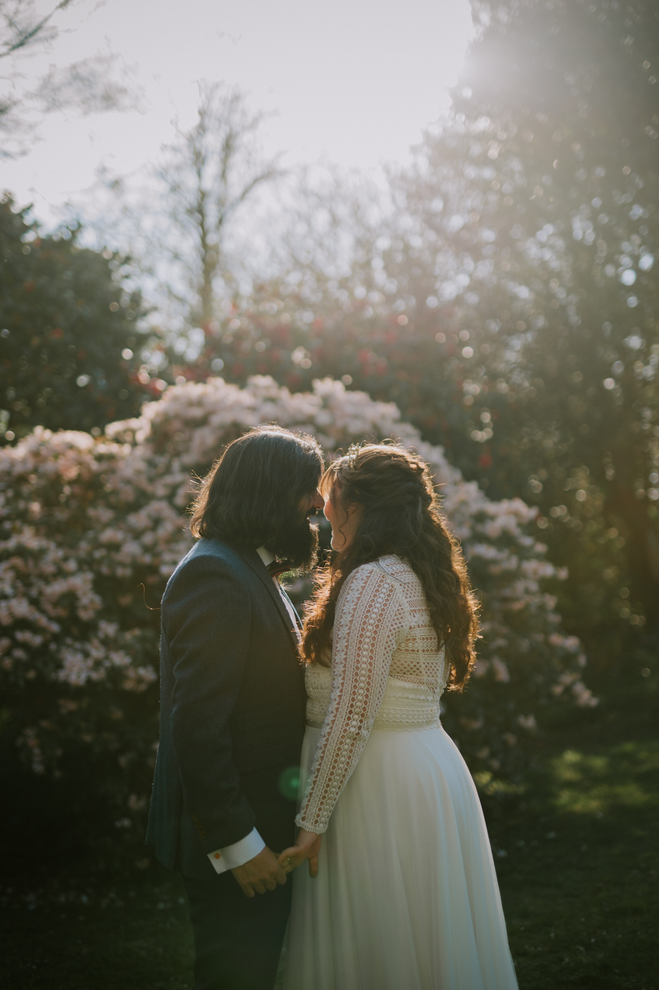 bride and groom in front of pink bush