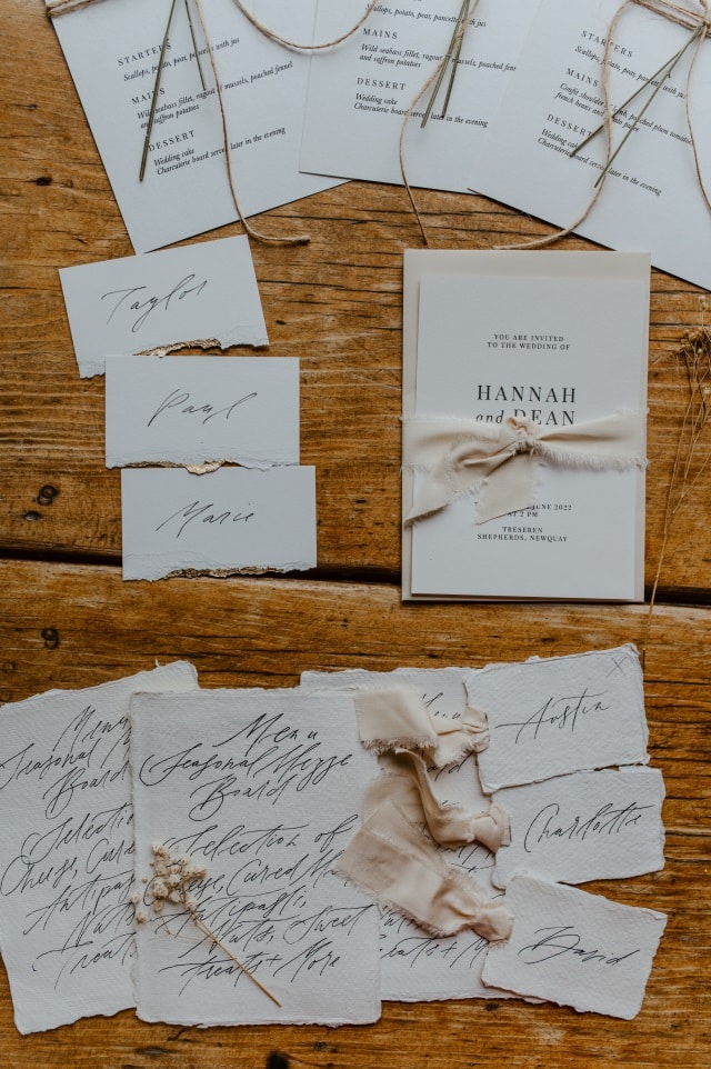 A table laid out with hand calligraphed stationery detailing menus and place settings.