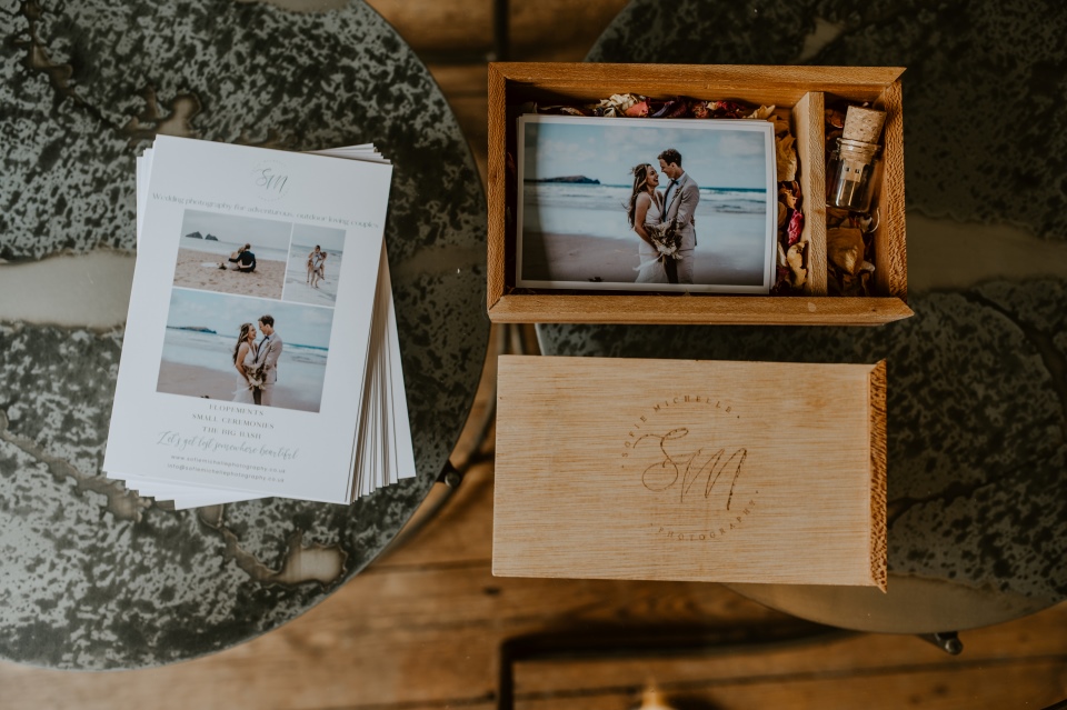 A glass table laid out with a wooden box and photo prints.