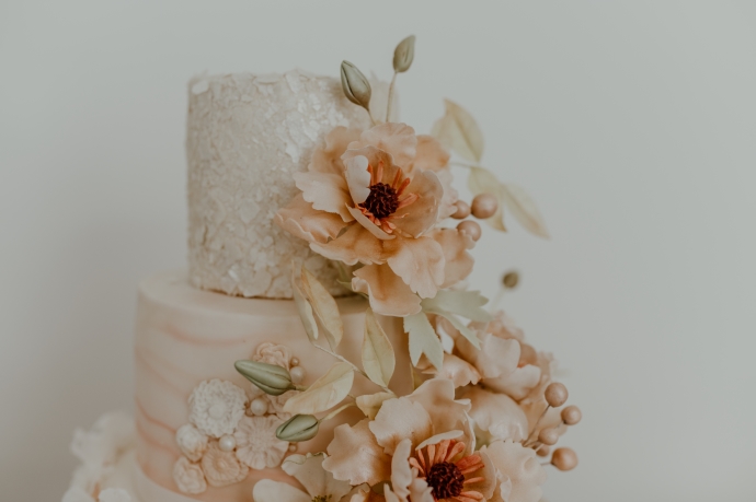 A three tier wedding cake, decorated with pink and white handmade flowers.