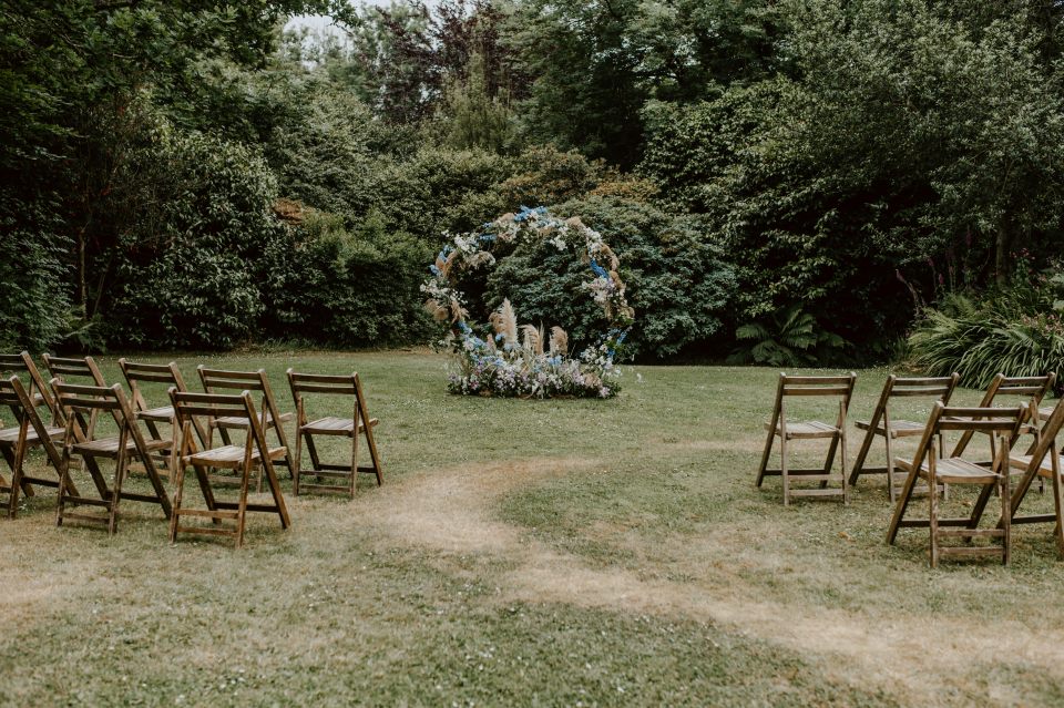 An outdoor small wedding ceremony set up at Treseren in Cornwall, with a floral arch.