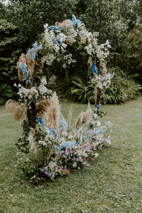 Outdoor wedding ceremony set up with wild flower floral arch.